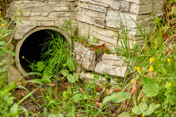 Naklejka premium Old pipe in a ditch to drain water
