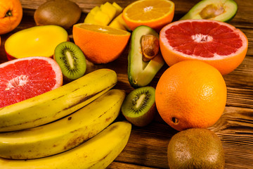 Still life with exotic fruits. Bananas, mango, oranges, avocado, grapefruit and kiwi fruits on wooden table