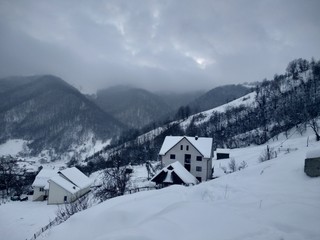 Paisaje de invierno con montañas y árboles, casas pueblo rural nieve en Rumanía Transilvania © nykaly