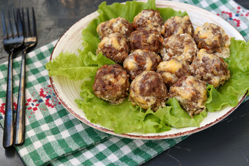 Meatballs in a sauce of cheese and sour cream are located in a plate on a dark background
