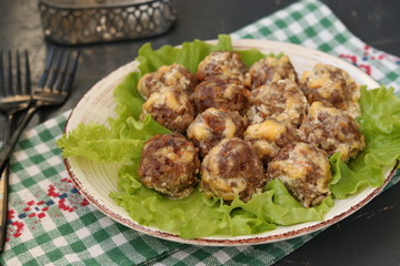 Meatballs in a sauce of cheese and sour cream are located in a plate on a dark background