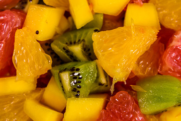 Background of the chopped exotic fruits. Mango, oranges, grapefruit and kiwi