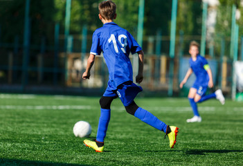 Junior football match. Boys in blue white sportswear play soccer match on football pitch. Football stadium, grass field at the background Soccer for young players. Training, sport, activity outdoor