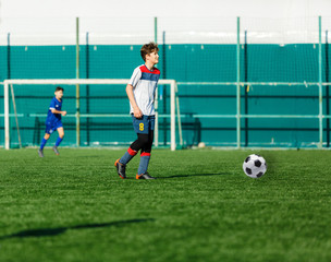Football teams boys in blue white sportswear play soccer on the green field. Dribbling skills.
