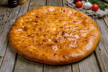 Ossetian pie with cheese on wooden board