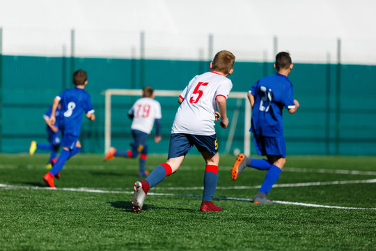 Junior football match. Boys in blue white sportswear play soccer match on football pitch. Football stadium, grass field at the background Soccer for young players. Training, sport, activity outdoor