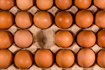 Pile of the hen eggs in paper tray on wooden table. Top view