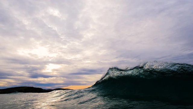 Multiple backwash waves cause several repeated sheets of glassy water to explode upward as wave breaks towards shore.  5x slow motion shot at 120 frames per second and dramatic moody skies and dark gr