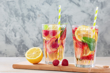 A refreshing drink with berries and lemon. Two glasses of lemonade with a straw. Bright summer photo.