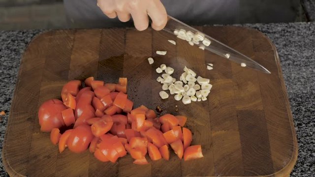 Chef slicing garlic on the cutting board with a knife