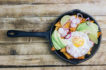 Homemade chilaquiles breakfast: nachos with tomato salsa, avocado and fried egg