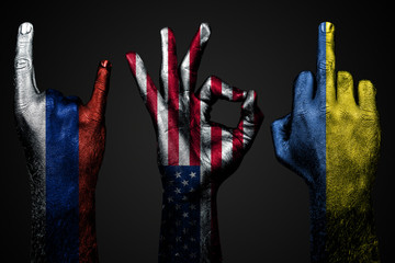 a set of three hands with a painted flag of Ukraine, Russia and USA show middle finger, goat and Okay, a sign of aggression, protest and approval on a dark background.