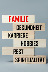 A list of wooden blocks lying on top of each other with a list of branches of human life in German, in the translation of the word: family, health, career, hobbies, relaxation, spirituality