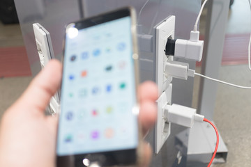 Female hands holding phone and using smartphone apps while charging it in a public place using...