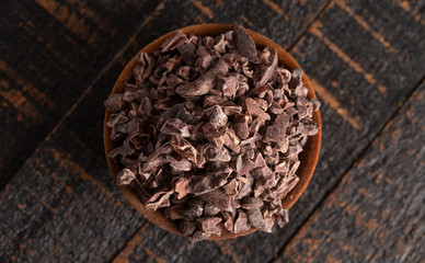 Bowl of Raw Chocolate Nibs on a Rustic Wooden Table
