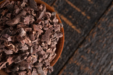 Bowl of Raw Chocolate Nibs on a Rustic Wooden Table