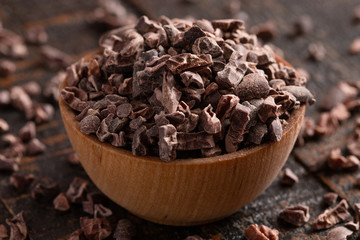 Bowl of Raw Chocolate Nibs on a Rustic Wooden Table