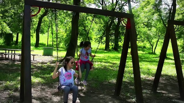 Happy girls swinging in the park, slow motion