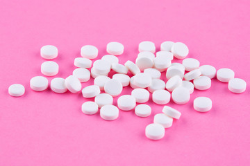 Heap of white pills on pink background