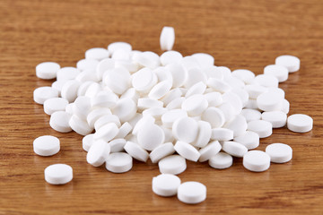 Fototapeta na wymiar Heap of white pills on wooden background