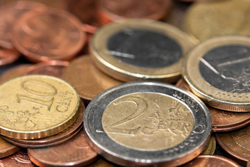 Different amounts of scattered European coins on a black background.