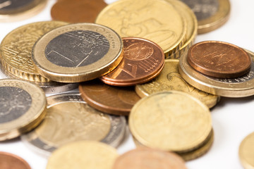 Different amounts of scattered European coins on a white background.