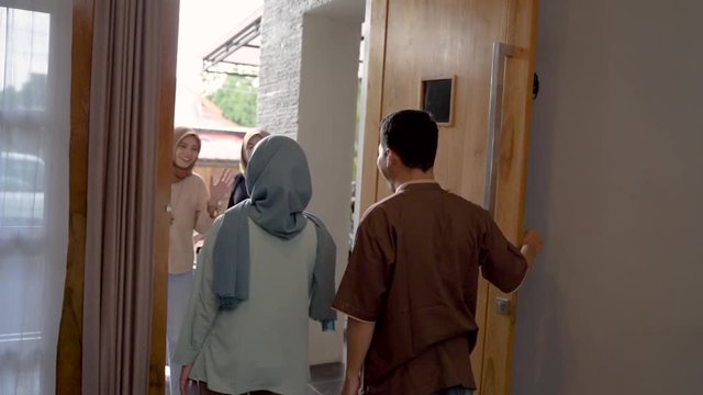 muslim friend and family visiting home and greet embrace each other celebrating eid mubarak