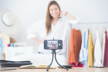 Beautiful asian woman blogger showing clothes in front of camera to recording vlog video live...