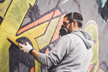 Street graffiti artist painting with a color spray can a graffiti on the wall in the city - Urban, lifestyle street art concept © Alessandro Biascioli