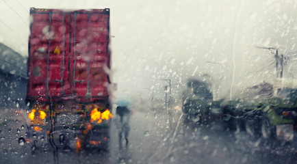 Blurry trucks ,view through the windshield of a car in the rain .Selective focus and color toned.
