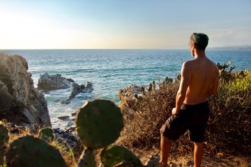 Homme regardant la mer torse nu sur une falaise de Puerto Escondido, Oaxaca, Mexique.