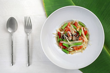 Papaya salad crab Thai food in a white plate on a white wood floor