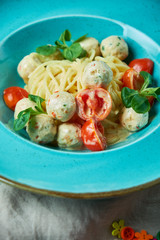 Children's pasta with meatballs and basil among children's toys 