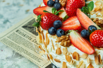 Strawberry meringue cake with almond petals, on newspaper 