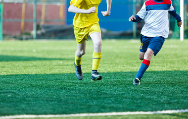 Football teams boys in yellow white sportswear play soccer on the green field. Dribbling skills. Team game, Training, active lifestyle, hobby, sport for kids concept