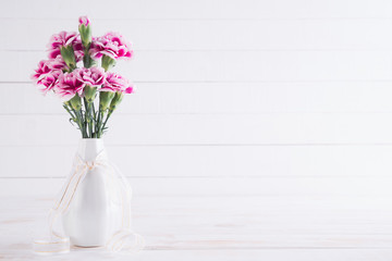 Valentines day and love concept. Pink carnation flower in vase on white wooden background.