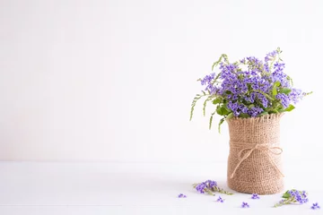 Fototapete lovely purple flower in sack vase on white wooden table. © Siam
