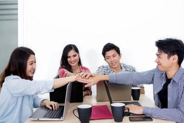 Young business team joining hands after a meeting