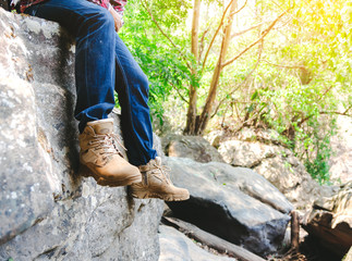 Hiking man with trekking boots sitting on rock in forest