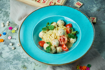Children's pasta with meatballs and basil among children's toys 