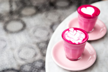 Obraz na płótnie Canvas Two glasses of pink beetroot latte with beautiful latte art on marble table background. Trendy healthy drink.