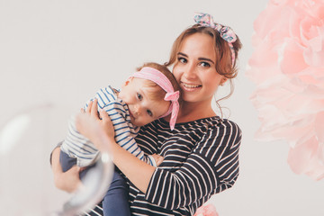 the child in the arms of his mother on white background. A woman with a child in her arms next to a large flower