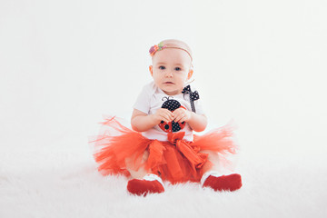 a little girl in a dress sits on the floor on a white background. Child promotes children's clothes