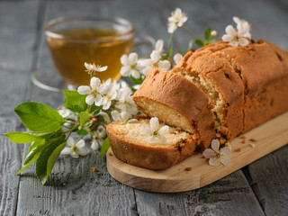 Freshly baked cake with raisins in cherry flowers and tea on a wooden table.