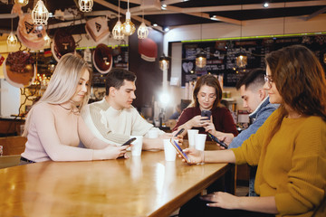 Five young handsome students sitting in a cafe.