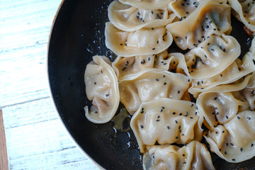A plate of fried dumplings sprinkled with sesame