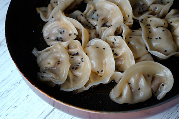 A plate of fried dumplings sprinkled with sesame