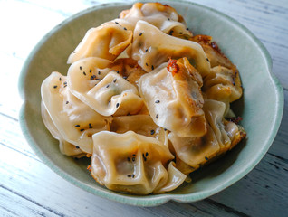 A plate of fried dumplings sprinkled with sesame