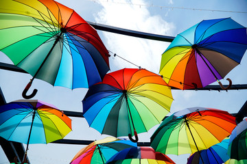 Colorful umbrellas background. Colorful umbrellas urban street decoration.  Hanging Multicolored umbrellas over blue sky. umbrellas with many colors