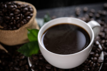 Hot coffee cup with coffee beans on the wooden table
